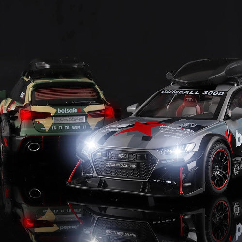 Dva modela Audi RS6 Avant automobila sa razlicitim dezenima i logotipima "Gumball 3000" i "betsafe" stoje jedan pored drugog na tamnoj reflektujucoj povrsini. Prednji automobil je srebrne boje sa crnim i crvenim detaljima i upaljenim prednjim svetlima. Zadnji automobil je maskirne zeleno-braon boje. Oba automobila imaju krovne nosace.