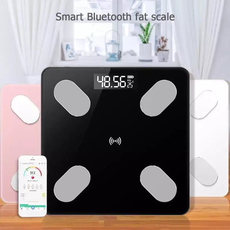 Crna pametna Bluetooth vaga za merenje telesne masti prikazuje težinu od 48.56 kg na digitalnom ekranu. Pored nje se nalazi pametni telefon sa uključenom aplikacijom koja prikazuje detaljne podatke o telesnoj kompoziciji, uključujući težinu od i druge metrike. U pozadini su vidljive druge vage u roze i beloj boji, kao i elementi kućnog dekora poput zavesa, slika, fenjera i biljaka.