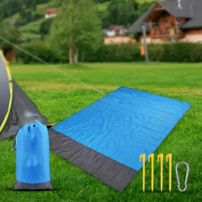 Plavo-siva prostirka rasirena na travi u parku, idealna za opustanje i piknik na otvorenom. Lako se cisti.