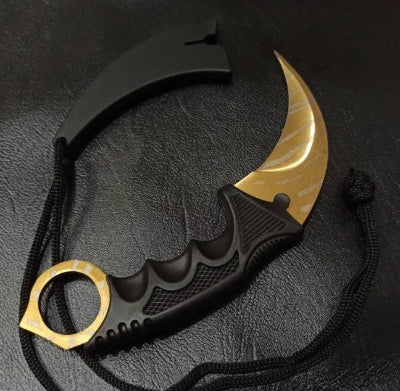 Karambit noz sa zlatnim secivom i crnom drskom. Nozevi su replike iz CS:GO video igrice.