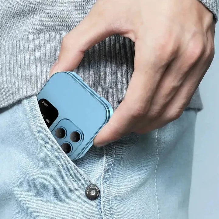 Svetloplavi mini preklopni telefon i16 Pro, zatvoren, smesten u dzepu svetlih farmerki, sa vidljivom trostrukom kamerom.
