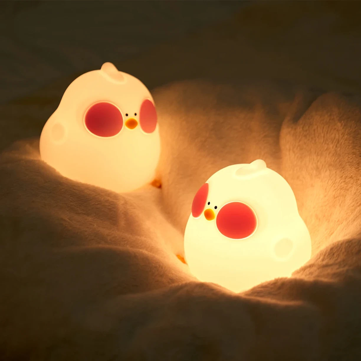 Dve silikonske nocne lampe pile na mekoj posteljini