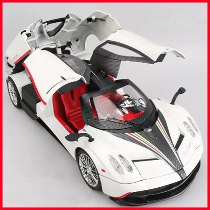 Model belog Pagani Huayra automobila sa otvorenim "leptir" vratima i zadnjim poklopcem. Unutrasnjost automobila je crvena. Model stoji na svetlosivoj povrsini, a ivice fotografije su crvene. Na haubi se nalazi crna pruga sa crvenim i zelenim detaljima.