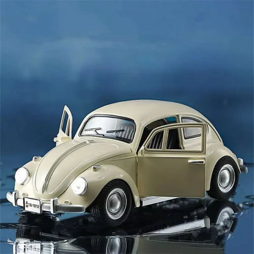 Model bež Volkswagen Beetle automobila sa otvorenim prednjim i zadnjim desnim vratima stoji na crnoj reflektujucoj povrsini. U pozadini je plava pozadina. Na prednjoj strani automobila vidi se registarska tablica sa natpisom "A 18-1812"