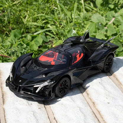 Model crnog sportskog automobila Apollo Evo sa crvenom unutrasnjosti postavljen je na svetloj kamenoj povrsini. U pozadini je zeleno lisce i trava, sto stvara kontrast sa sjajnom crnom bojom automobila.