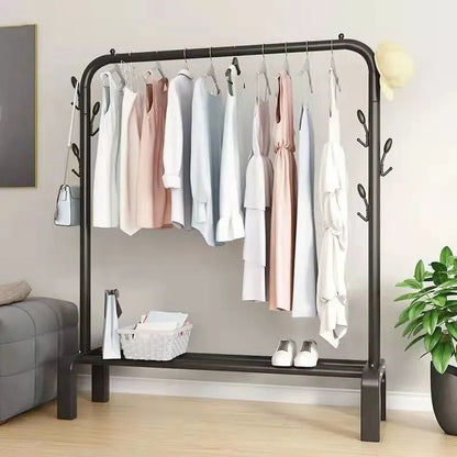 Stalak za odecu sa torbom koja visi sa strane, pletenom korpom i belim patikama na donjoj polici.