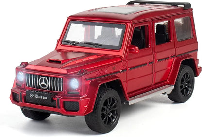 Model crvenog Mercedes-Benz G-Klase, sa oznakom "G-Klessa" na prednjoj masci, stoji na beloj pozadini sa upaljenim prednjim svetlima. Model ima crne točkove i krovne nosače.