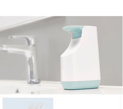 Dozator tecnog sapuna bele i svetloplave boje pored slavine, savrsen dodatak za moderno kupatilo ili kuhinju, elegantan dizajn.