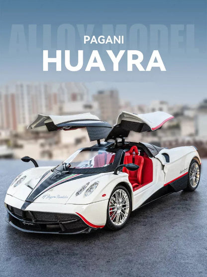  Detaljan model belog Pagani Huayra automobila sa otvorenim vratima i crvenim enterijerom postavljen je na sivoj povrsini. U pozadini je zamucena urbana panorama ispod plavog neba. 