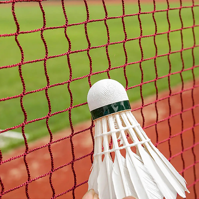 Detalj crvene mreže za badminton, loptica perjanica, sportska oprema za takmičenje, izdržljiva mreža za dvoranu i na otvorenom.