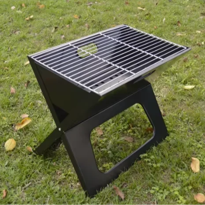 Stabilni prenosivi rostilj za ugalj postavljen na travnatoj povrsini. Celicni sklopivi gril za prirodu i izlete. Visok kvalitet izrade.