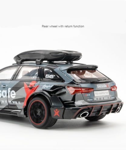 Detaljan prikaz zadnjeg dela modela srebrnog Audi RS6 Avant automobila sa "betsafe" i "Gumball 3000" oznakama. Automobil ima krovni nosac i crvene detalje oko zadnjih svetala i branika. U gornjem delu pise zadnji tocak sa povratnom funkcijom.
