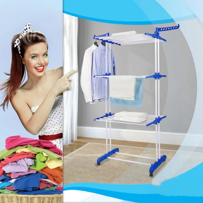 Nasmejana zena sa gomilom sarenog vesa u korpi pokazuje prstom prema stalku za susenje vesa na tri nivoa.