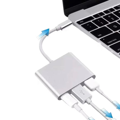 Srebrni USB C razdelnik sa istovremeno prikljucena tri razlicita kabla ukljucena u bocni port laptopa