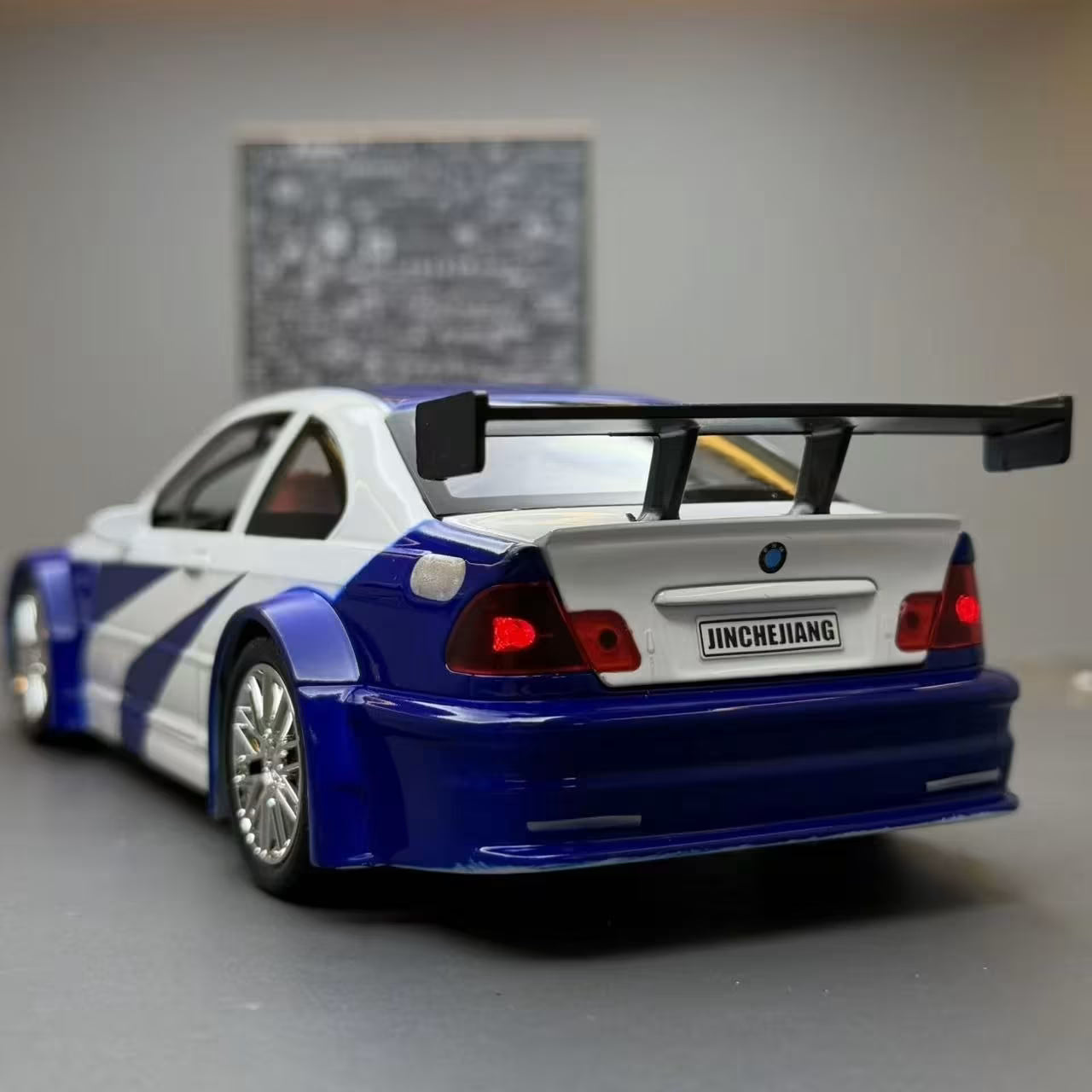 Zadnji deo BMW M3 E46 sa velikim spojlerom i upaljenim crvenim stop svetlima