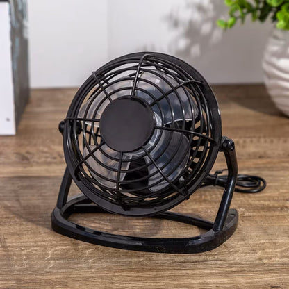 Mali crni ventilator za osvezenje i hladjenje tokom rada na kompjuteru slikan na drvenoj podlozi