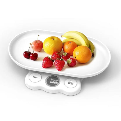 Bela digitalna kuhinjska vaga sa ovalnim tasom na kome se nalazi raznovrsno sveže voće poput jagoda, pomorandži i banana
