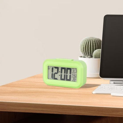 Zeleni digitalni budilnik postavljen na radnom stolu pored laptopa