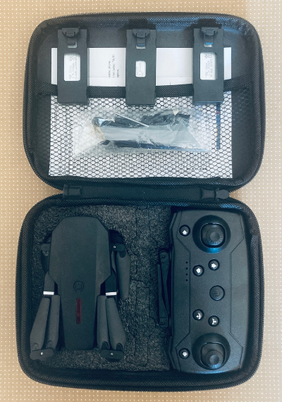 Unutrasnjost kofera sa organizovanom opremom za dron, ukljucujuci daljinski upravljac i dodatke.