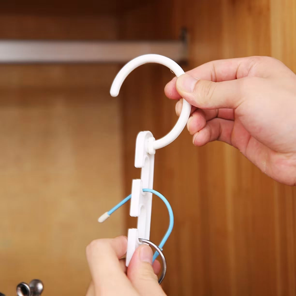 Ruka drzi beli plasticni organizator sa zakackom i prorezima za kacenje vesalica