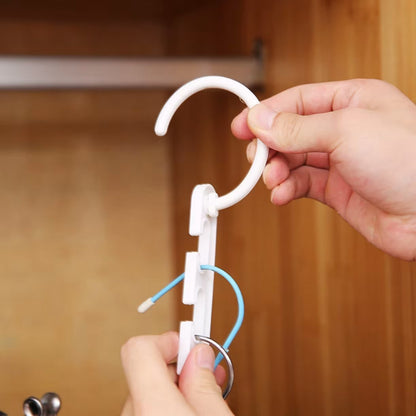 Ruka drzi beli plasticni organizator sa zakackom i prorezima za kacenje vesalica