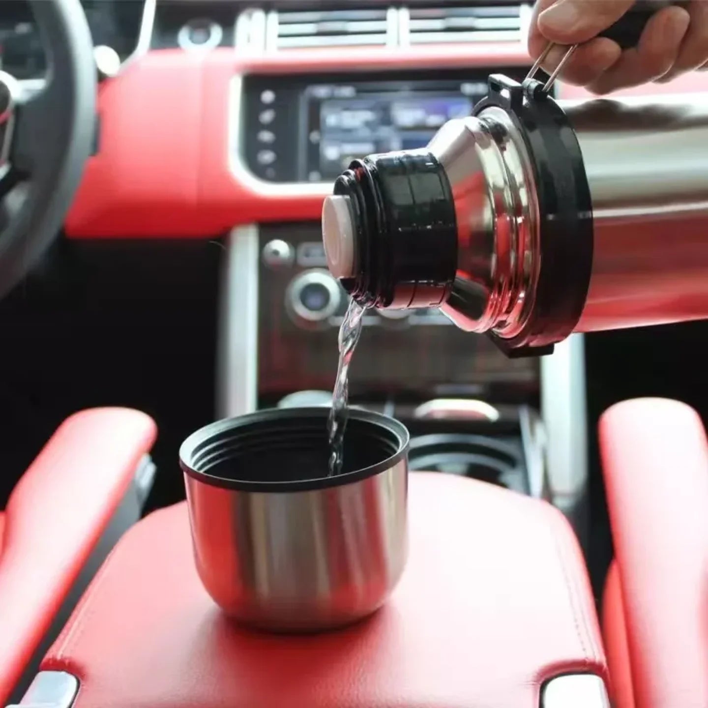 Sipanje napitka iz inoksnog termosa u casu u automobilu