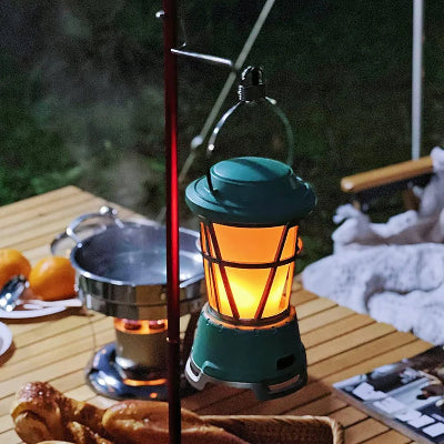 Lampa za kampovanje osvetljava sto u prirodi. Stvara prijatnu atmosferu za veceru ili odmor.