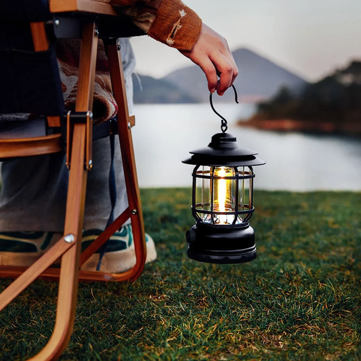 Osoba drzi retro kampersku lampu pored jezera