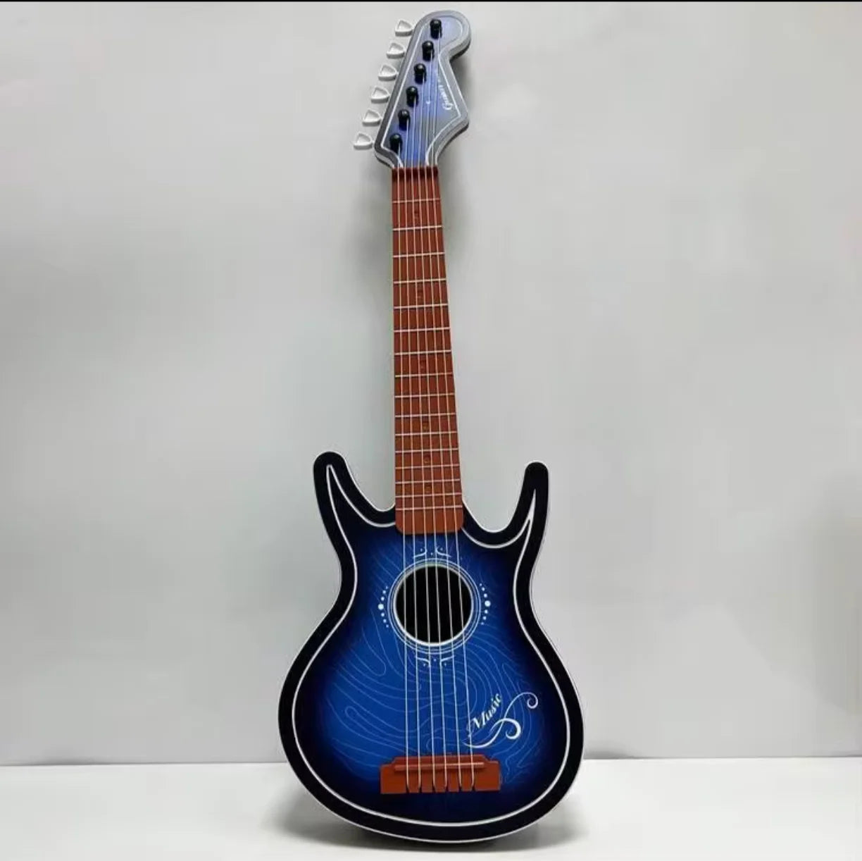 Plava decija drvena gitara igracka na sivoj pozadini