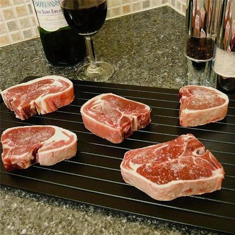 Ploca za brzo odmrzavanje mesa sa steak komadima na kuhinjskoj radnoj povrsini