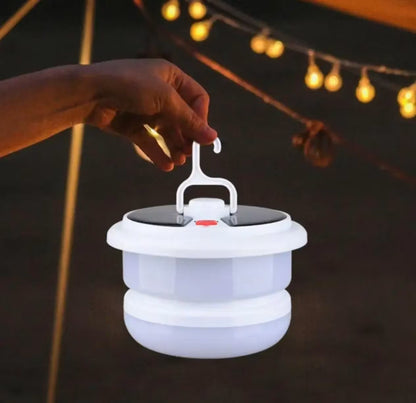 Ruka drži belu solarnu kamping lampu za gornju kuku