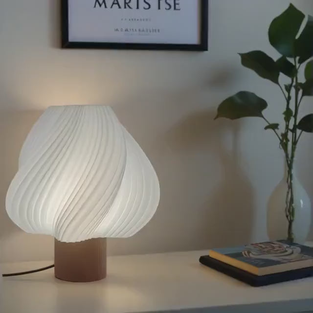 Dizajnerska stolna lampa spiralnog oblika prikazana u radu sa ambijentalnim svetlom u modernom enterijeru