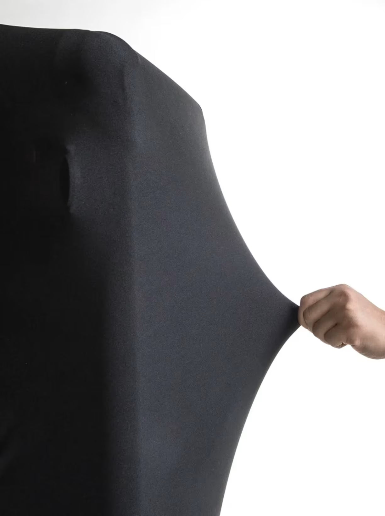 Ruka koja rasteze crnu tkaninu navlake prikazujuci elasticnost i prilagodljivost dimenzijama