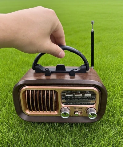 Mali radio prijemnik u ruci na travi za izlete i prirodu laka prenosivost izdrzljiva izrada