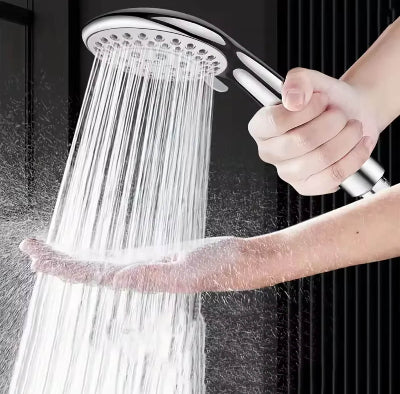 Osoba drzi rucni tus pod jakim mlazom vode, prakticna upotreba.