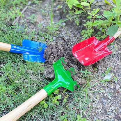 Tri sarena rucna alata zabodena u crnu zemlju i travu tokom uredjenja baste