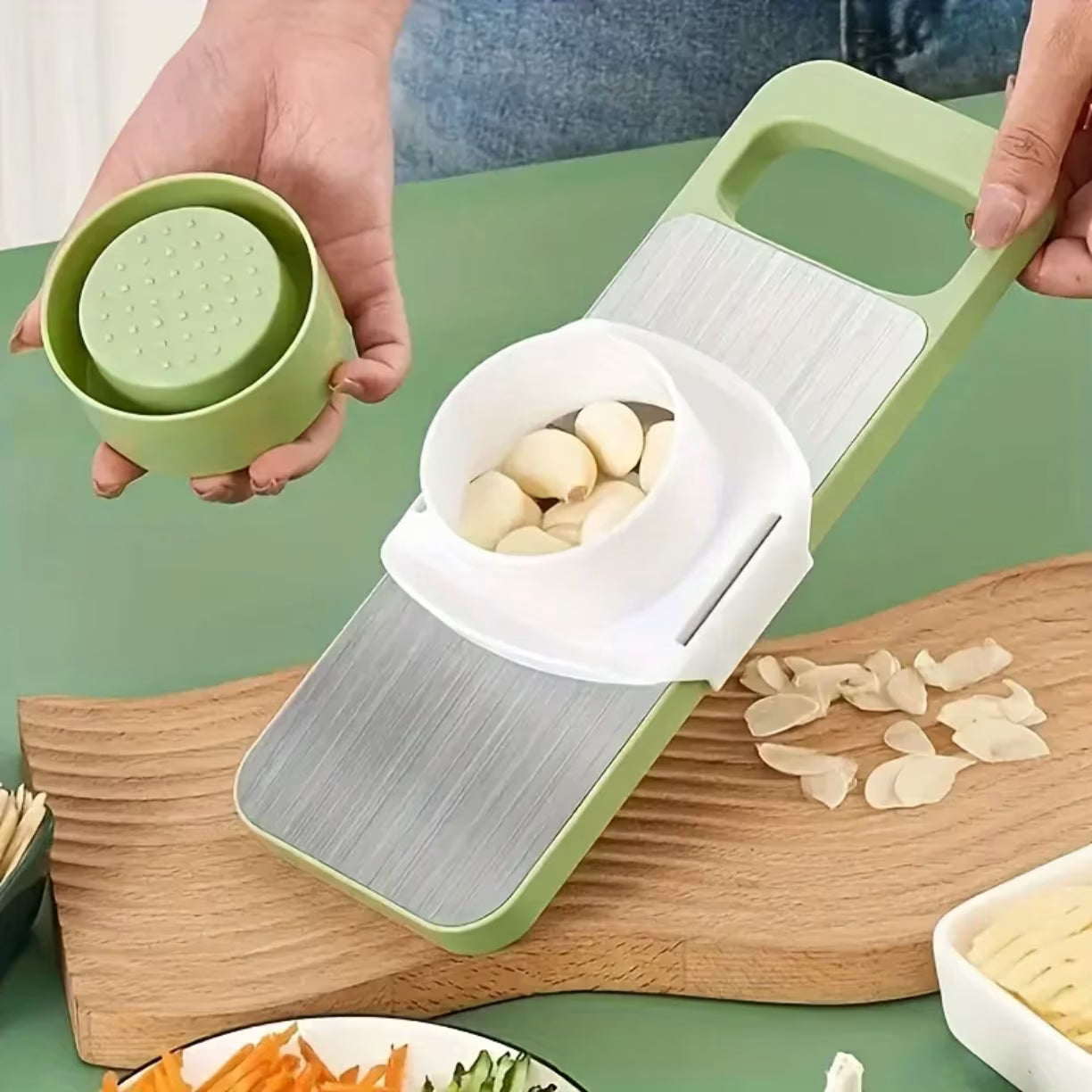Prikaz secenja cena belog luka pomocu belog plasticnog nastavka i zelenog rendeta na drvenoj kuhinjskoj dasci