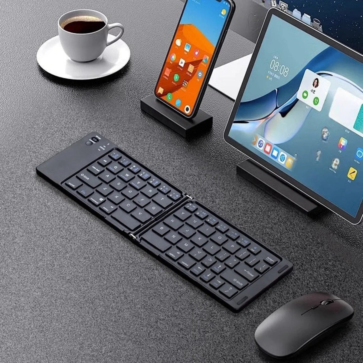 Otvorena sklopiva bluetooth tastatura na stolu uz telefon i tablet