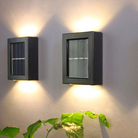 Solarne zidne lampe sa toplim svetlom na zidu iznad biljke