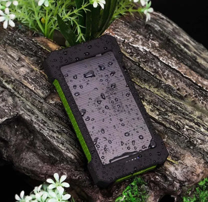 Solarni power bank sa kapljicama vode na kucistu u prirodnom okruzenju