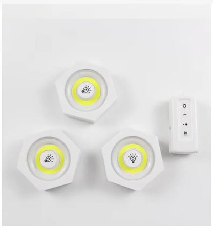 Komplet od tri bele bezicne lampe rasporedjene pored duguljastog daljinskog upravljaca sa oznakama za paljenje gasi i tajmer