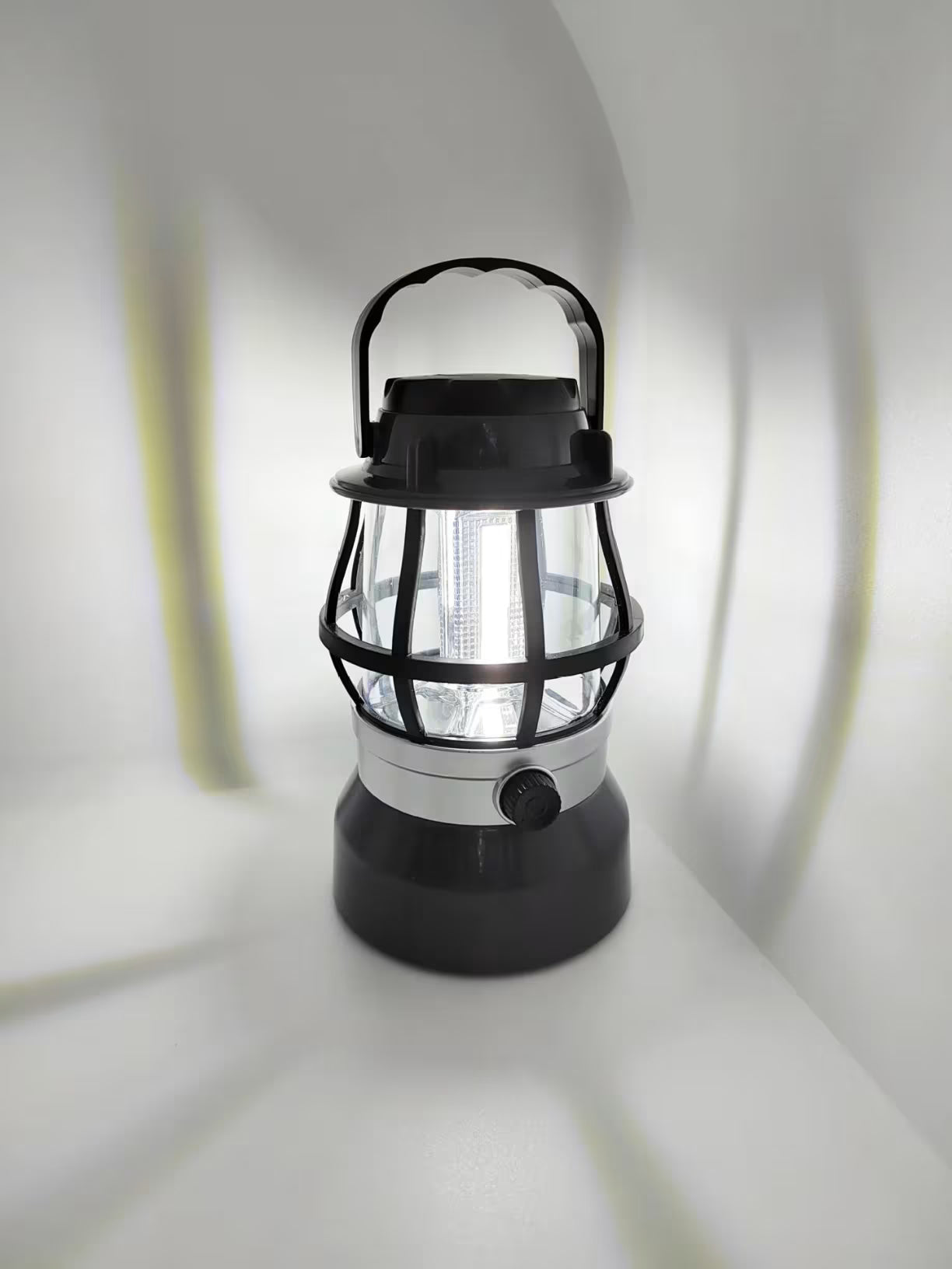 Crna plasticna lampa retro dizajna sa upaljenim jakim led svetlom unutar zastitne resetke na beloj pozadini
