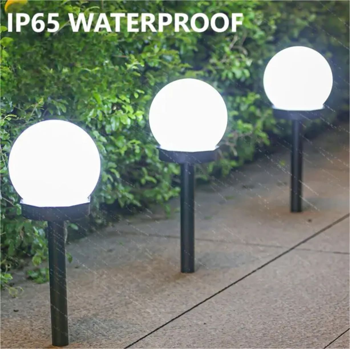 Tri dvorisne solarne lampe u obliku kugli koje svetle na kiši sa istaknutim natpisom IP65 Waterproof u gornjem delu slike