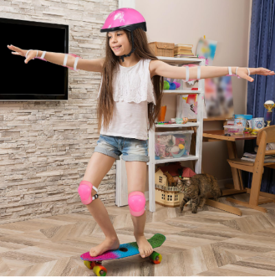 Devojcica na skejtbordu nosi zastitnu opremu. Zastitni set za ucenje voznje i bezbednost.