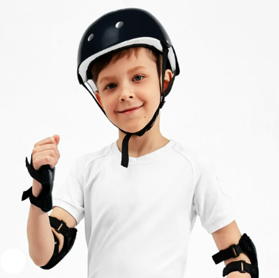 Decak nosi crni komplet zastitne opreme. Kaciga i stitnici za kolena, laktove i ruke za bezbedne sportske aktivnosti.