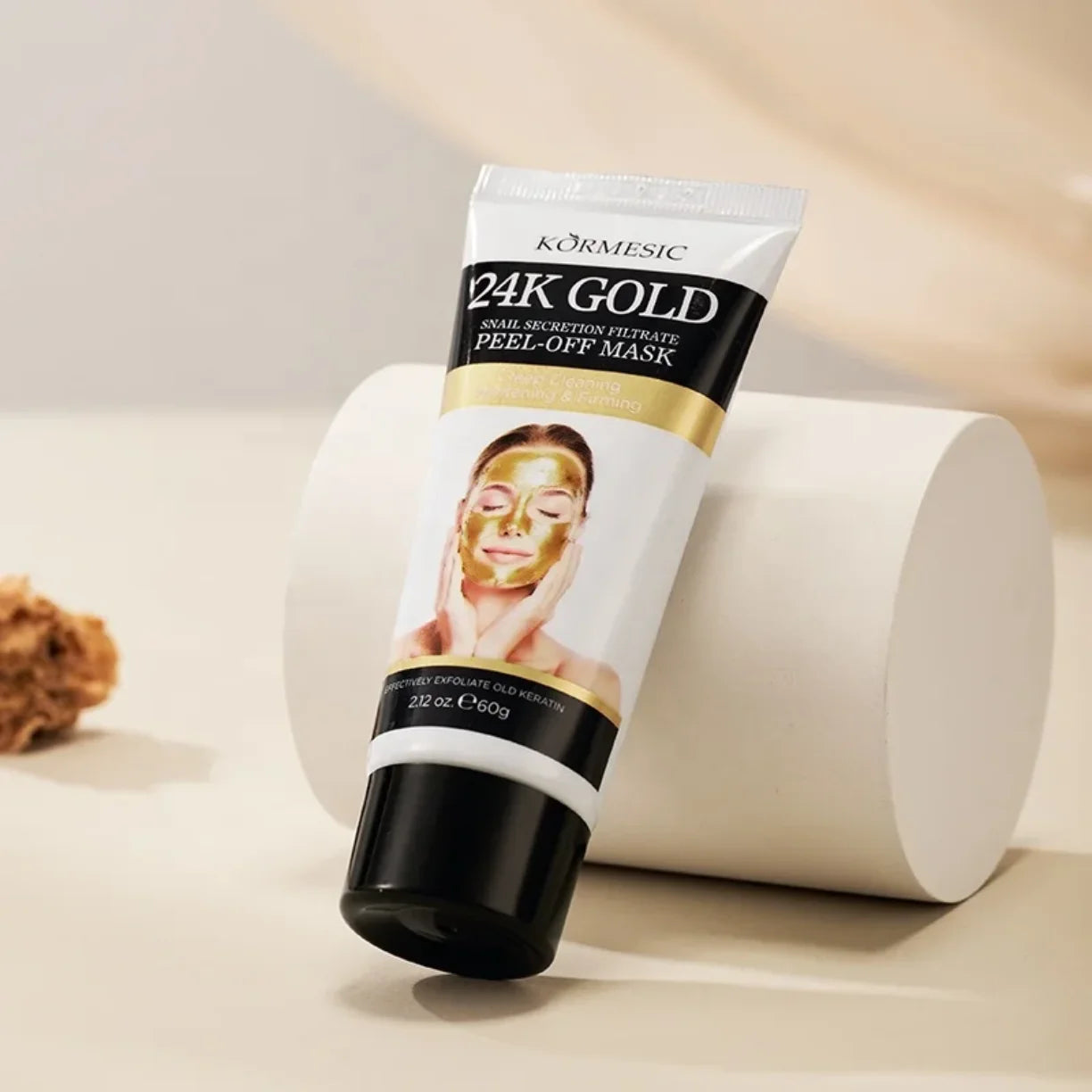 Tuba zlatne peel off maske za lice naslonjena na belo postolje